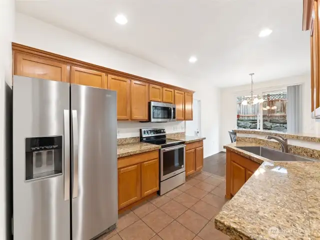 Spacious kitchen offering a breakfast bar, granite counters & updated stainless appliances.