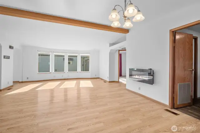 Open living area with hardwood floors, bright windows, and a cozy fireplace that conveys. Door on the right leads to the utility room.