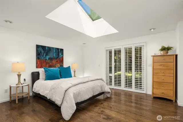 Primary bedroom featuring beautiful hardwoods, floor to ceiling shutters, huge skylight with programmable powered sun shade and slider leading to the back yard.