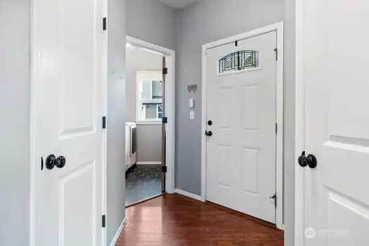 Looking back towards entry door you can see the laundry room.  Notice all the unique angles and lines.  White panel doors, dark floors and high ceilings.