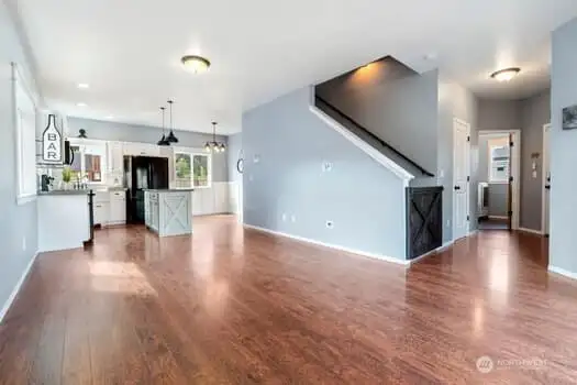 A great view of the open living room looking toward the kitchen and dining area and showcasing the staircase to the upper level with custom gate.