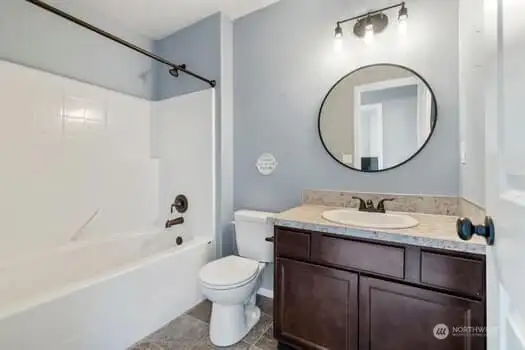 Main bath upstairs has modern lighting and cabinetry and bronze hardware as accents.