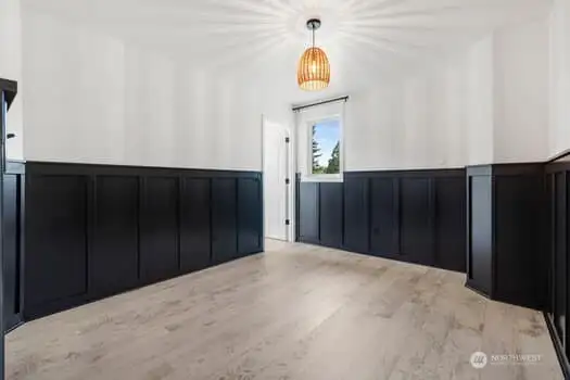 2nd bedroom with black wainscoting, venting window and walk in closet.  Flooring is unique in all the bedrooms with beautiful patterned white wash look.