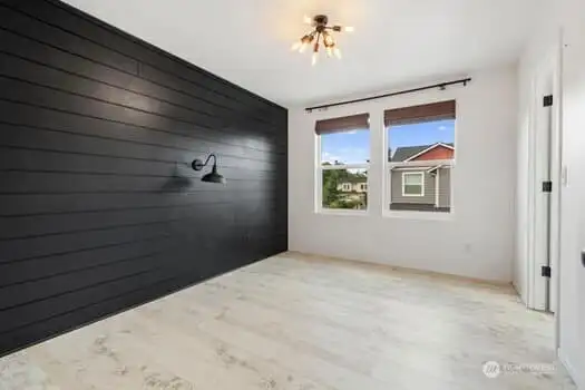 Bedroom 3 has two venting windows with wooden blinds, black shiplap wall and walk in closet. The lwall light iis for decor purposes only, otherwise non functional.
