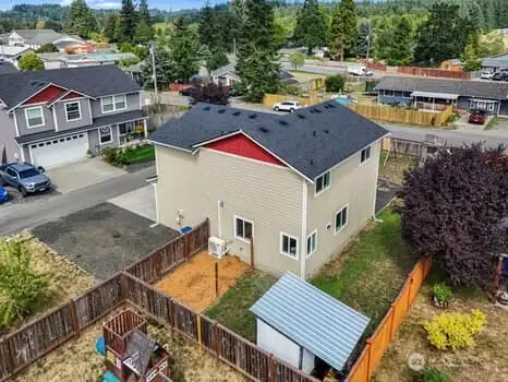 Drone view of the side of the home.  Garden area, storage shed, parking  and a small view of the new heat pump.