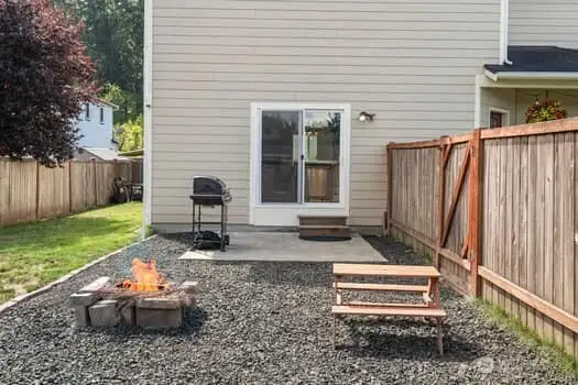 Close up of patio off sliders, fire pit and graveled area next to lawn