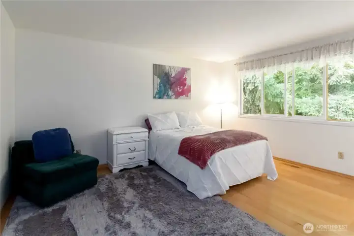 Bright and inviting upstairs primary bedroom with large windows and hardwood floors.