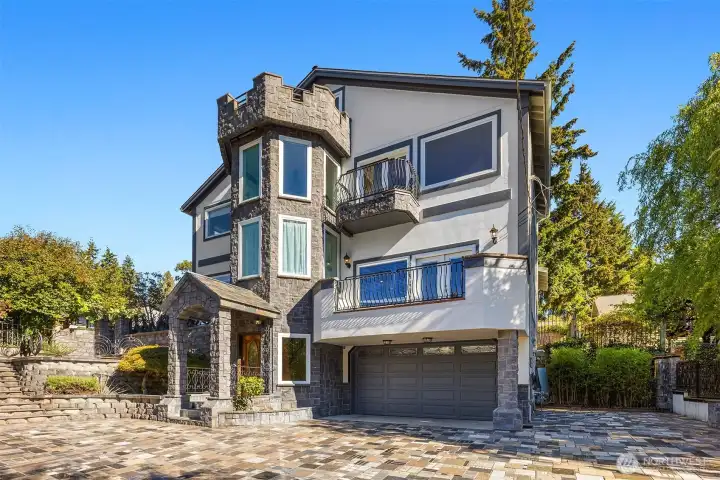 Gated entry leads to large driveway laid with granite stone, and 2-car garage.