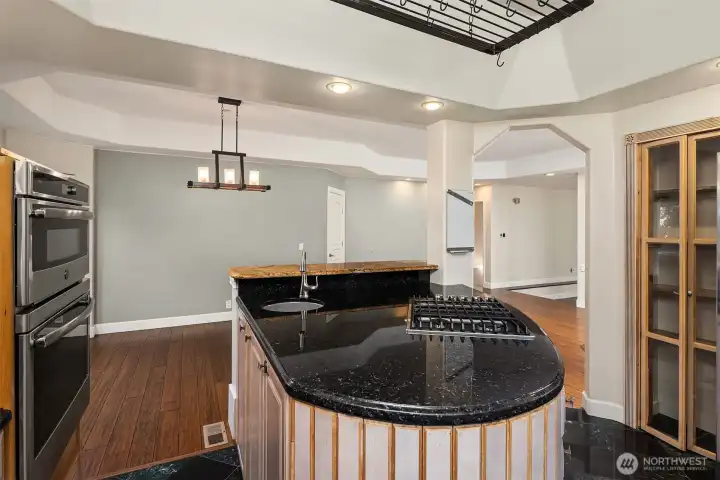 Kitchen includes double oven, island sink, gas range, and floor-to-ceiling glassware storage.