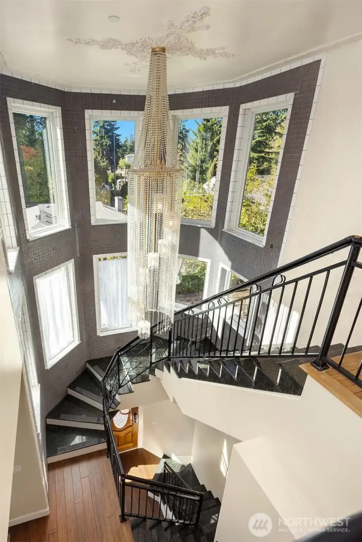 Incredible stairwell curving from the entry, to the the main and upper floors. Includes custom metal railings and wall tile, and 2-story wall of windows.