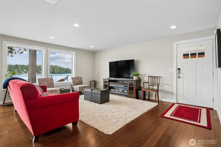 What a way to make an entrance! The front door opens straight into a living room that immediately pulls your attention past the warm wood floors and out toward Mason Lake like it knows exactly what the star of the show is. Those oversized windows frame 60 feet of golden shoreline waterfront with western exposure that absolutely shows off at sunset. The whole space feels open, relaxed and ready for lake life, with enough room for guests to spill in comfortably after a day on the dock without everyone tripping over each other at the entry, while that soft cream-and-white palette keeps everything feeling calm, bright and very easy to live in.