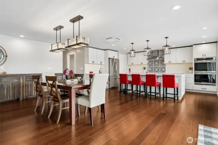 The dining area and kitchen connect seamlessly, creating one large entertaining space where everyone stays part of the action, but importantly, nobody feels crammed together balancing a plate on their lap. The layout gives each space enough breathing room to actually function well, and then the kitchen decides to show off a little with crisp white cabinetry, black hardware and that dramatic double wall oven setup immediately elevating the room into “someone here definitely cooks” territory. Whether it is holiday dinners, wine-and-cheese nights, pancake breakfasts after the lake, or one very overconfident Thanksgiving turkey situation, this kitchen is ready.