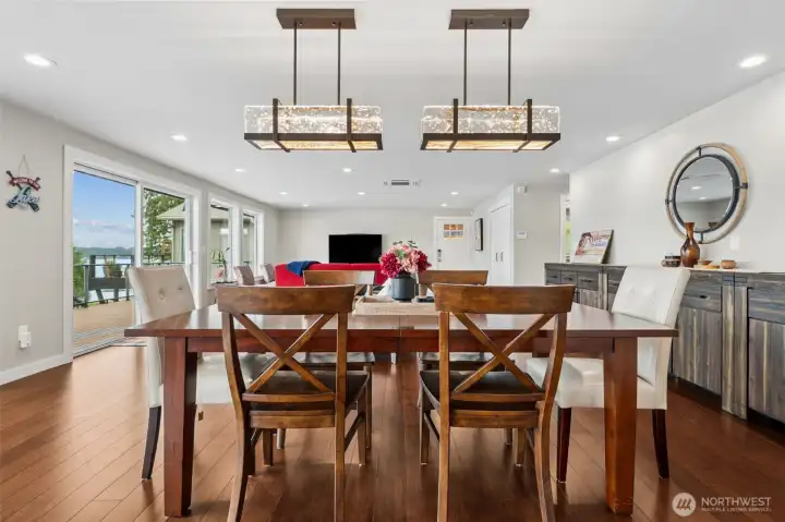 This angle really captures the rhythm of the space. The dining area feels connected to the living room and lake views beyond, while still holding its own as a true gathering space anchored by those gorgeous matching chandeliers overhead. They add just the right amount of polish and drama without fighting the view, which frankly would be a losing battle anyway. The sliding glass door leading to the new deck keeps the whole room tied to the outdoors, making it dangerously easy for dinner to drift outside with a glass of wine and suddenly become a sunset situation, so everything flows beautifully here. Open, airy, social and very lake-life coded.