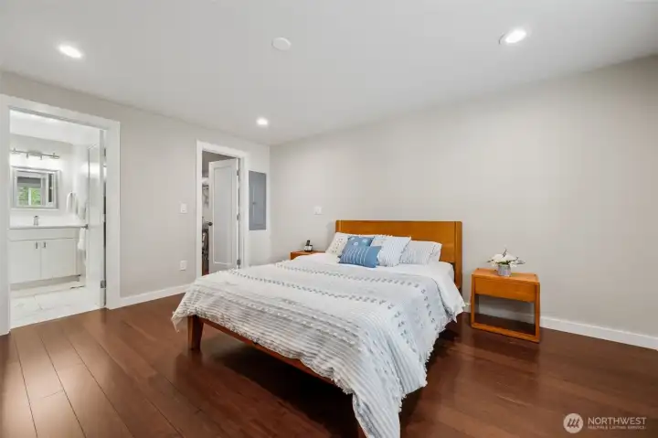 This angle of the primary suite really highlights something buyers love more and more every year, mostly main-floor living that actually supports staying put comfortably through every stage of life. The primary bedroom, en suite bath, main gathering spaces, kitchen and lake views are all right here on the main level, making the home feel easy, functional and wonderfully livable long term. From this view you can also see the walk-in closet and private bathroom entrance, creating a true suite setup instead of just a bedroom with a bathroom nearby pretending to be fancy. The room itself still feels spacious and calm, with enough flexibility to evolve as life changes.