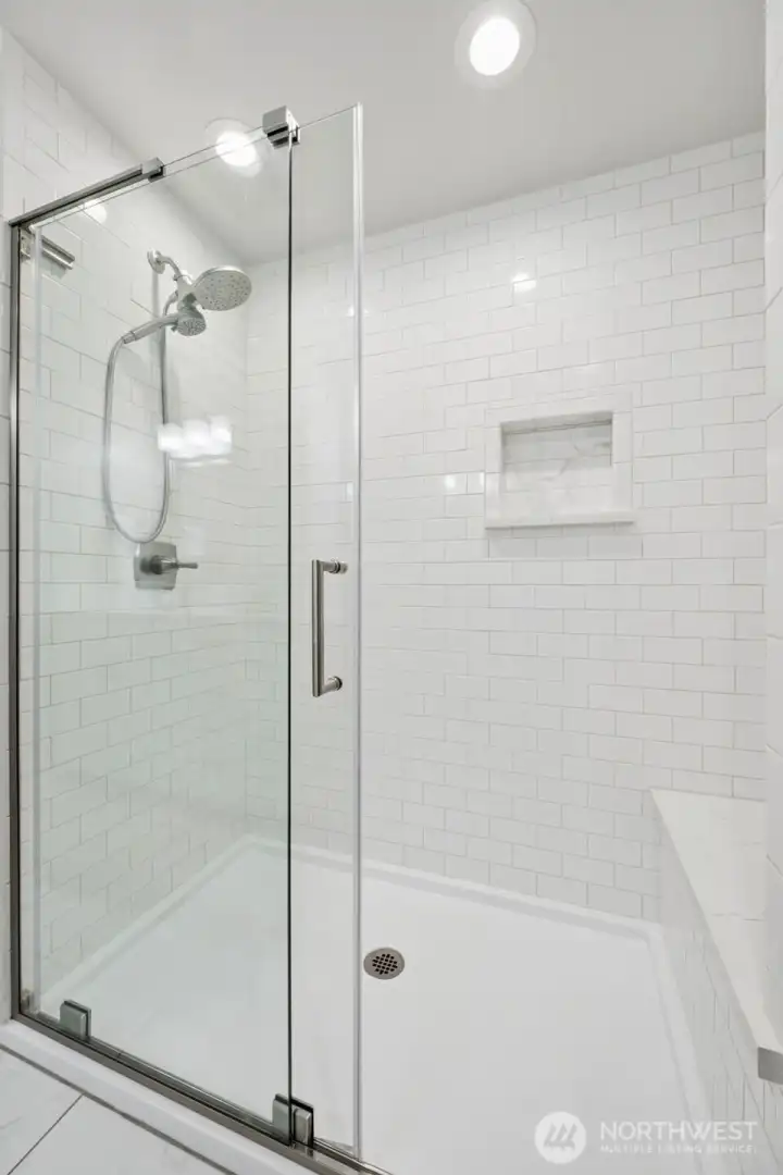 The low-threshold tiled shower gives a clean modern look while also making the space feel practical and easy for long-term living. Dual shower heads, bench seating and sliding glass doors bring a polished spa-like feel without tipping into anything overly fussy. And paired with the enormous 7x11 walk-in closet nearby, this suite starts feeling genuinely substantial. Not “technically a walk-in closet,” but an actual room-sized dressing and storage situation.