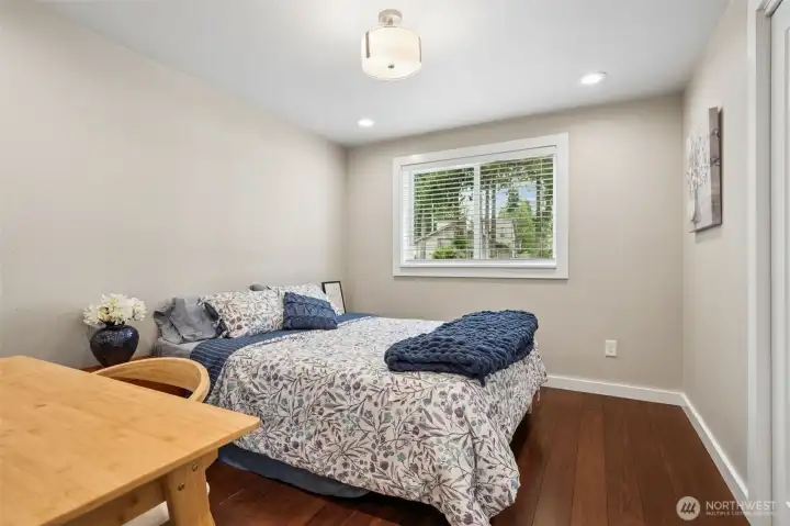 This bedroom keeps the same relaxed, elevated tone flowing through the rest of the home with warm hardwood floors, creamy white paint tones and soft natural light creating a space that feels fresh and very easy to personalize, while the drum-style fixture overhead adds a little classic charm. At approximately 10’x11’, there is room here for more than just “technically fitting” furniture too. It comfortably handles a larger bed setup while still leaving breathing room. And the split-bedroom floor plan deserves some applause here. This bedroom sits near the primary suite, while two additional bedrooms are tucked farther away near the front of the home, giving the layout a flexibility that works beautifully for guests, multigenerational living, home office needs or simply a little extra privacy when everyone is under one roof.