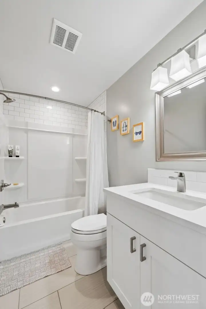 This third bathroom continues the same clean, cohesive design language carried throughout the home, crisp white vanity, undermount sink, neutral tones and a full tub/shower surround ready for guests, kids or serious bubble bath energy after a long lake day. Positioned near the kitchen-side bedroom wing in the split-bedroom layout, it serves that side of the home beautifully while still feeling connected and convenient, and beyond the finishes, there are some very smart behind-the-scenes details worth appreciating too. Water sensors have been installed near the laundry area, refrigerator, dishwasher and water heater to help alert owners to leaks early, which honestly feels like the kind of practical luxury more homes should have. The home also operates on a 3-party shared well at only about $350 per year toward maintenance, giving you plentiful water without the larger utility bills.