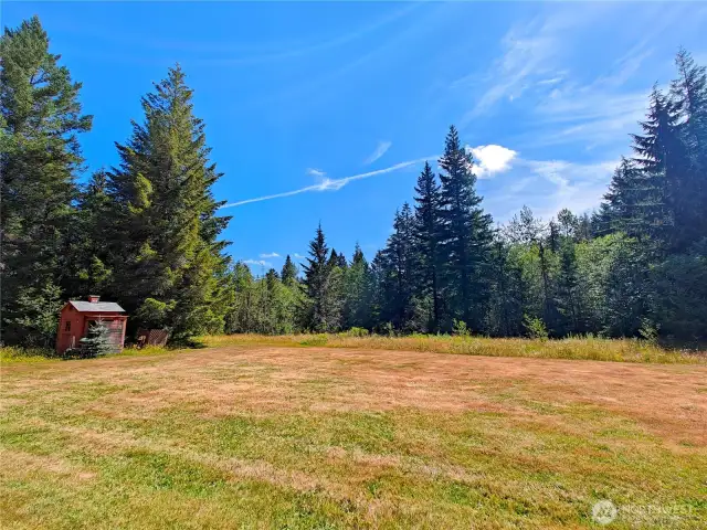 Sweeping views of the well maintained backyard with a small greenhouse.