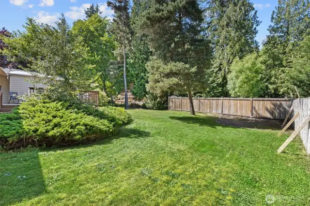 Fully fenced backyard is a great mix of open green grass and garden space.
