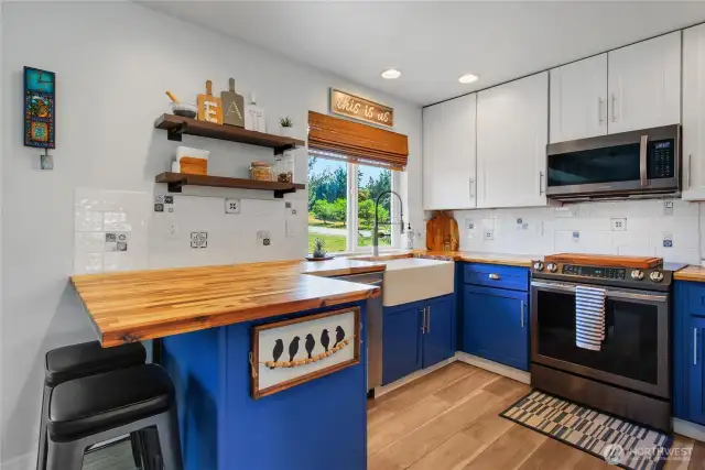 Open kitchen with updated appliances and butcher block counters