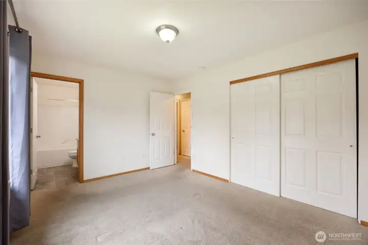Primary bedroom with full bath, two door closet, and backyard view.