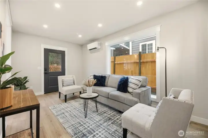 The great room has a large window and has a second door leading to the patio. You will see one of the mini split heat pumps that heats and cools the home.