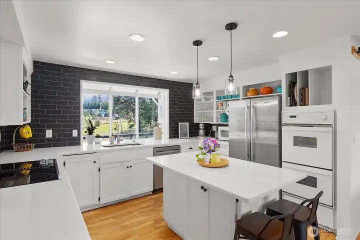 Tastefully updated country kitchen with garden window, full wall tile backsplash and quartz countertops.