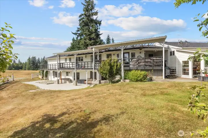 Back of house with expansive covered deck,   freshly poured patio and adorable   greenhouse off to the right.