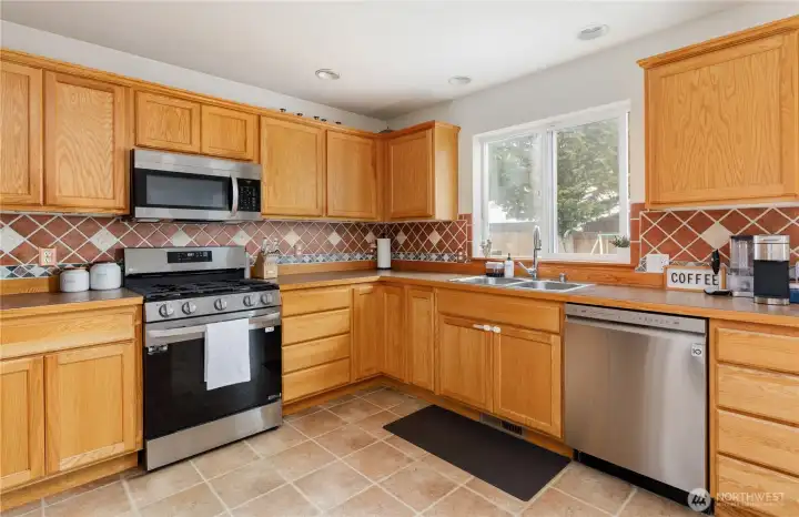 An open, beautiful, kitchen with newer stainless steel appliances.