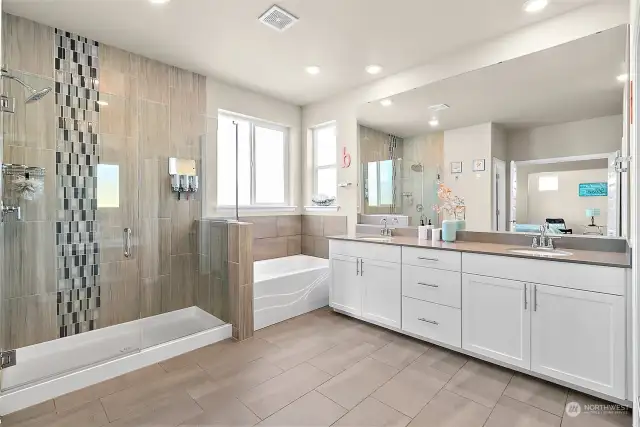 Indulge in a spa-like experience with a stunning primary bath that features a large walk-in shower, showcasing elegant floor-to-ceiling tile and a decorative glass tile for added interest.