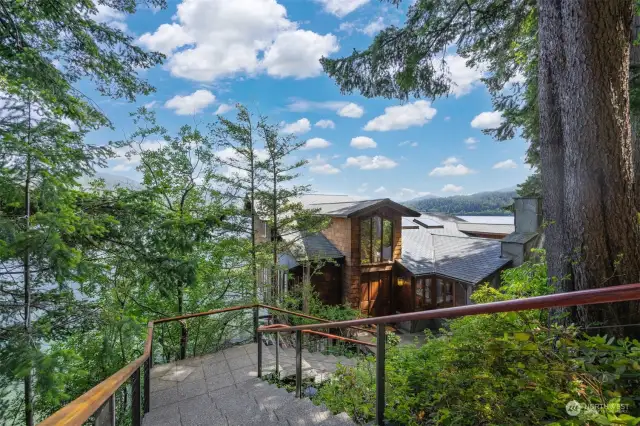 Looking down at the front entry of the home built into the side of the lake and facing east.