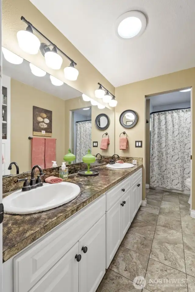 The guest bath also includes a pocket door to the primary bedroom and enjoys double sinks.