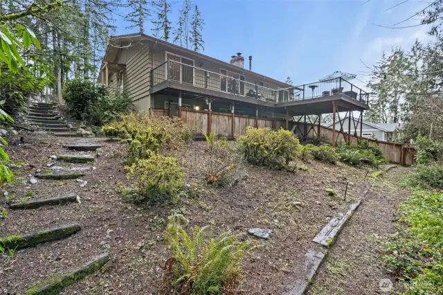 A view of the back of the home from the sloped yard. Notice the amazing deck with so much space for relaxing and entertaining.