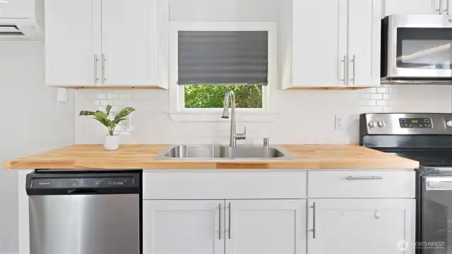 Crisp white shaker cabinets pair beautifully with a deep double-basin sink and a high-arch faucet—classic, clean, and ready to handle real life!
