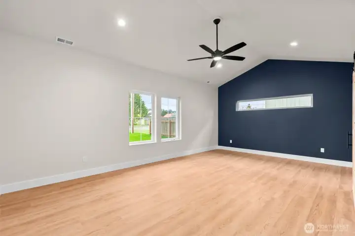 Inviting primary suite complemented by the vaulted ceiling, large windows, and ceiling fan.