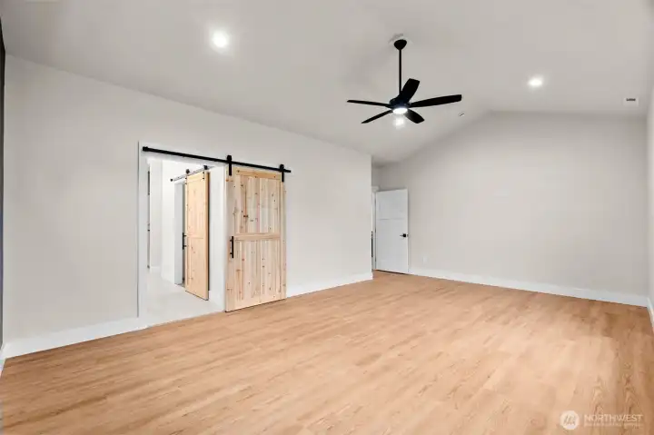 Spacious primary suite with warm natural pine barn doors, offering a perfect blend of comfort and character.