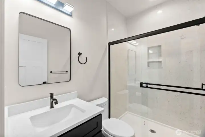 Guest bathroom finished with sleek fixtures and thoughtfully selected details. Outlet behind the toilet for future bidet set-up.