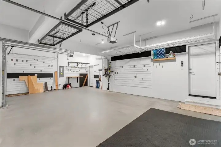Oversized 3-car garage with EV chargers, garage wall slat storage and built-in overhead storage racks.