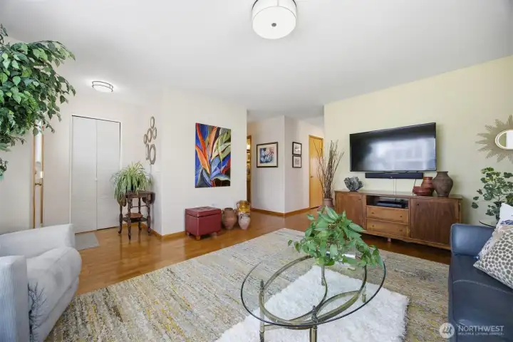 Looking across the living room toward the entry to the left with a large coat closet and the hallway to the 2nd bedroom and the kitchen to the right.