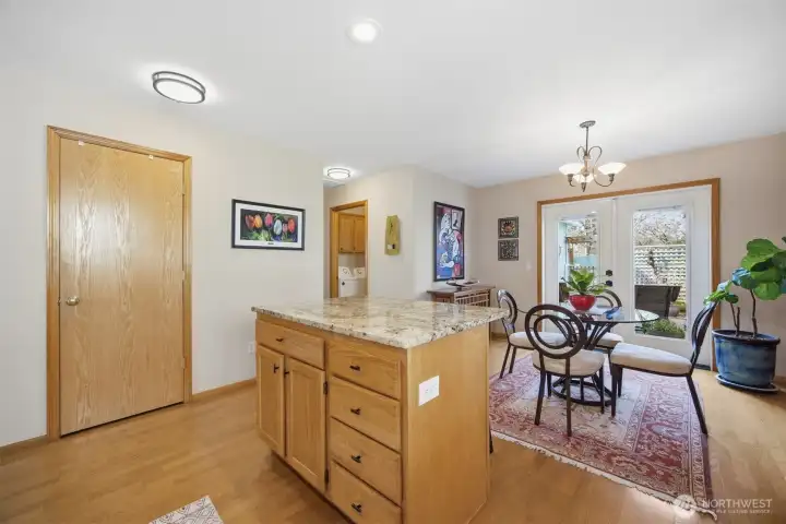 Looking across the kitchen with the pantry beyond the island and the laundry room between the French doors and the primary bedroom suite.