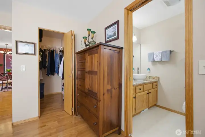 Another view from the primary suite with the bathroom with the granite counter and vessel sink, and the walk-in closet to the left.