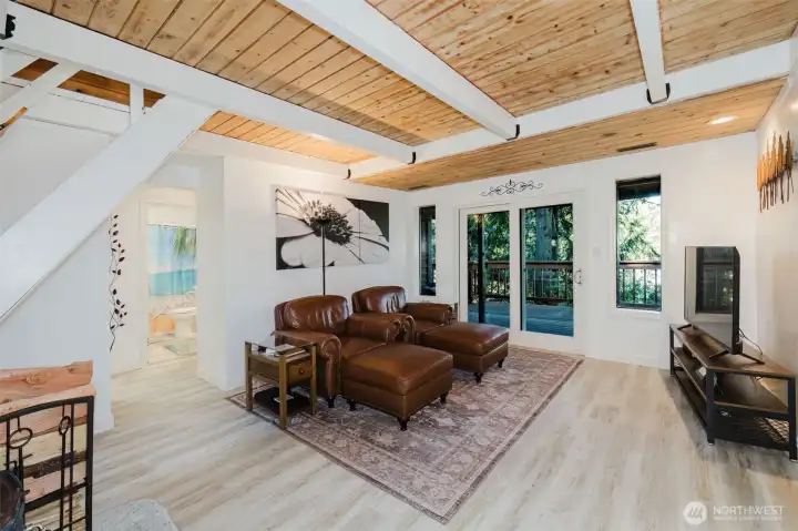 Naturally beautiful living area with tongue and groove ceilings, doors and windows to deck and view of lake.  Feels like a treehouse from this side of the house.