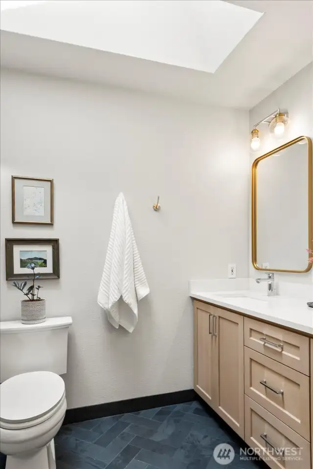 Primary en-suite bathroom with skylight, heated floors and custom rift white oak vanity. Herringbone black slate floors