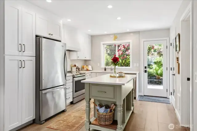 Open kitchen with island, stainless steel appliances, pantry storage and quartz countertops