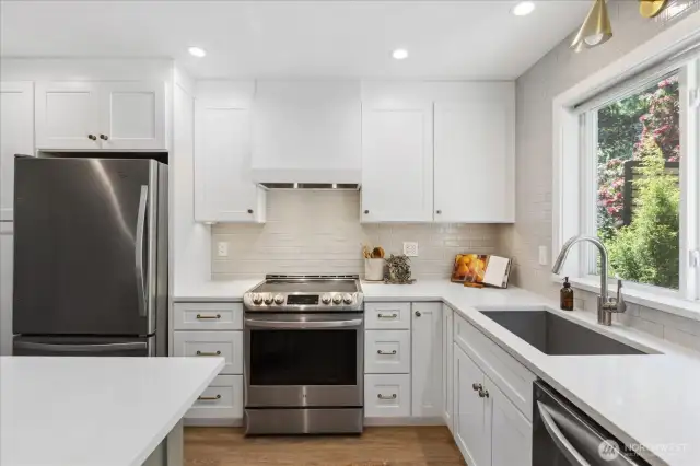 Updated kitchen with new shaker cabinetry, stainless appliances, tiled backsplash to the ceiling,quartz, and island.