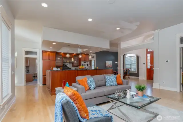 Bright and open great room seamlessly flows into the chef’s kitchen, featuring a spacious island, pendant lighting, and rich wood cabinetry—perfect for entertaining.