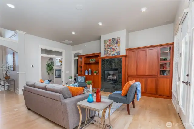 Inviting great room with custom built-ins, cozy fireplace, and walls of windows that fill the space with natural light—ideal for relaxing or entertaining.