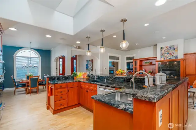 Stunning kitchen with cherry cabinetry, dramatic granite counters, and pendant lighting—open to the dining area with arched window, creating an ideal flow for entertaining.
