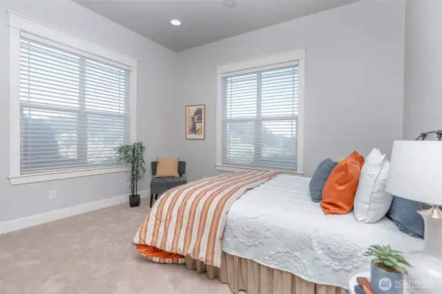 Bright and comfortable secondary bedroom with oversized windows, soft neutral palette, and plenty of natural light—ideal as a guest room or flexible living space.
