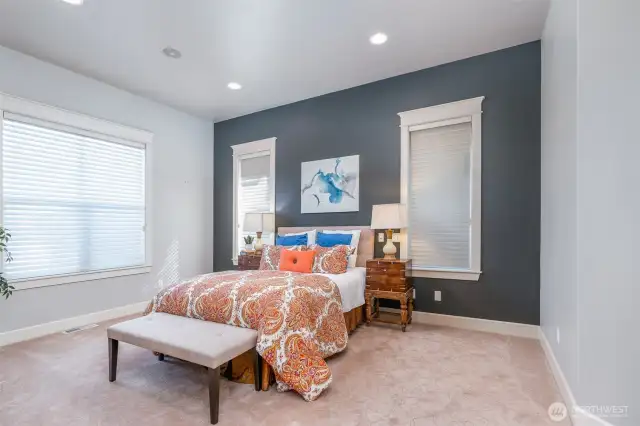 Expansive primary suite with accent wall, tall windows, and recessed lighting—offering a serene retreat with direct access to its own private sitting area and double-sided fireplace.